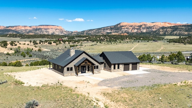 exterior space with driveway, a chimney, stone siding, and a mountain view