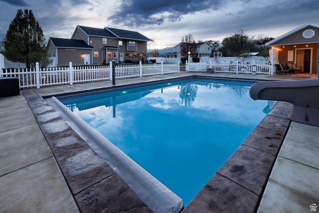 pool at dusk with a patio and a water slide