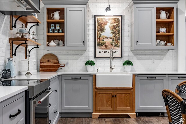 4250 S Camille St, Holladay, UT 84124 - kitchen with dark wood-type flooring, sink, stainless steel range with electric cooktop, brick wall, and backsplash
