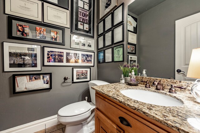 bathroom featuring tile flooring, toilet, and vanity with extensive cabinet space