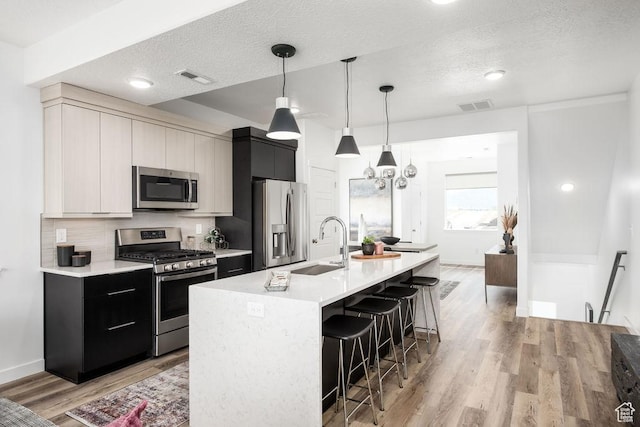 4126 S Winder Ward Dr Unit 2-123, Millcreek, UT 84124 - kitchen with appliances with stainless steel finishes, a sink, a breakfast bar area, light countertops, and light wood-style flooring