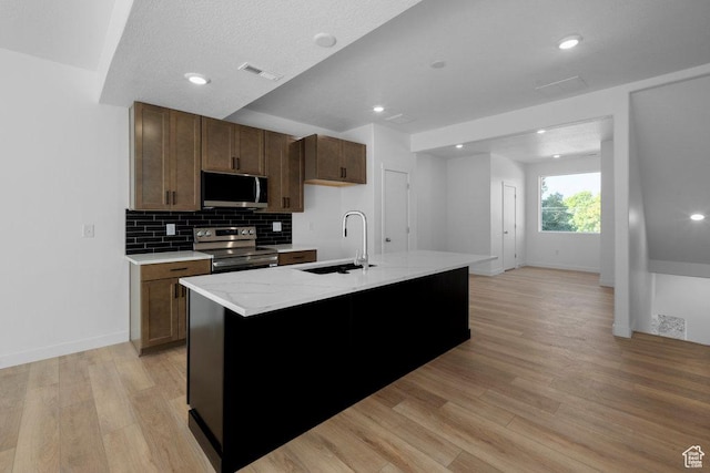 4126 S Winder Ward Dr Unit 2-123, Millcreek, UT 84124 - kitchen featuring appliances with stainless steel finishes, a sink, light wood finished floors, decorative backsplash, and baseboards