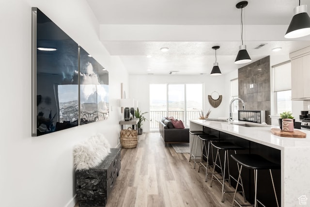 4126 S Winder Ward Dr Unit 2-123, Millcreek, UT 84124 - kitchen featuring modern cabinets, light countertops, light wood-style floors, a kitchen bar, and hanging light fixtures