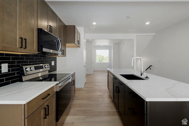 4126 S Winder Ward Dr Unit 2-123, Millcreek, UT 84124 - kitchen with appliances with stainless steel finishes, a sink, light wood-style flooring, backsplash, and light stone countertops