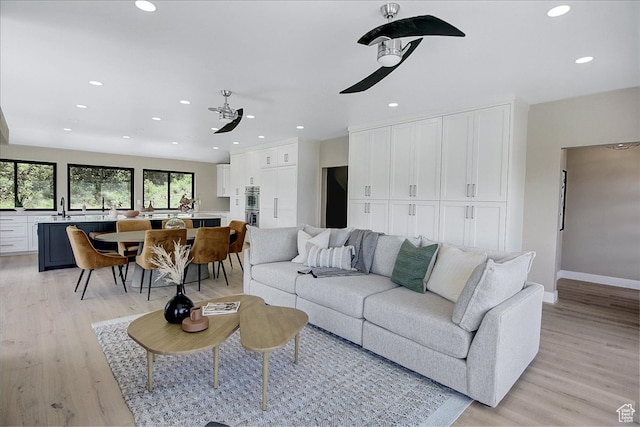 living room with ceiling fan, light hardwood / wood-style floors, and sink