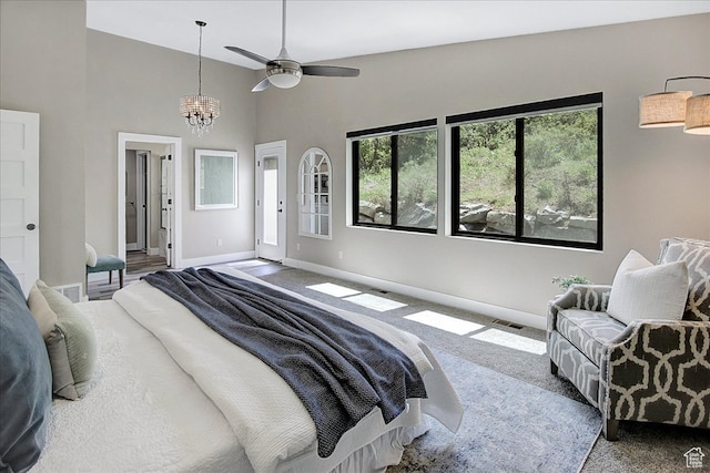carpeted bedroom featuring high vaulted ceiling and ceiling fan with notable chandelier