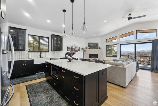 1430 W Arapaho Dr Unit 59, Coalville, UT 84017 - kitchen with a stone fireplace, a center island, stainless steel fridge with ice dispenser, light wood-type flooring, and pendant lighting