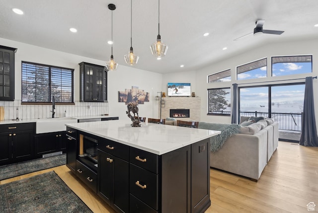 1430 W Arapaho Dr Unit 59, Coalville, UT 84017 - kitchen featuring a stone fireplace, black microwave, sink, hanging light fixtures, and a center island