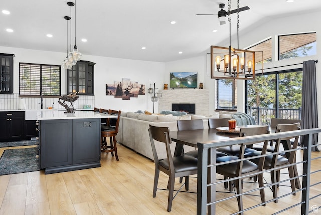 1430 W Arapaho Dr Unit 59, Coalville, UT 84017 - dining space featuring a stone fireplace, ceiling fan with notable chandelier, lofted ceiling, and light hardwood / wood-style flooring