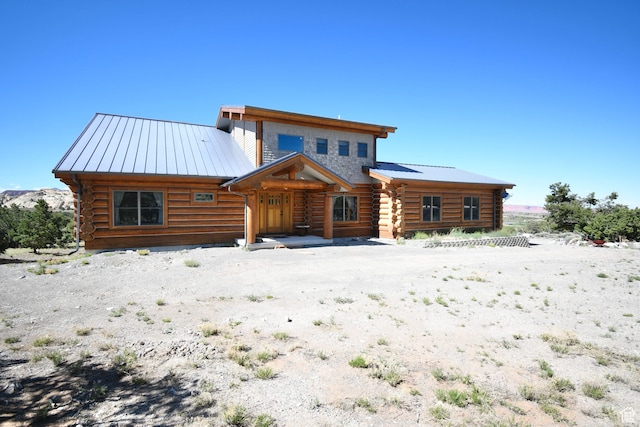 back of house featuring a standing seam roof, log siding, and metal roof