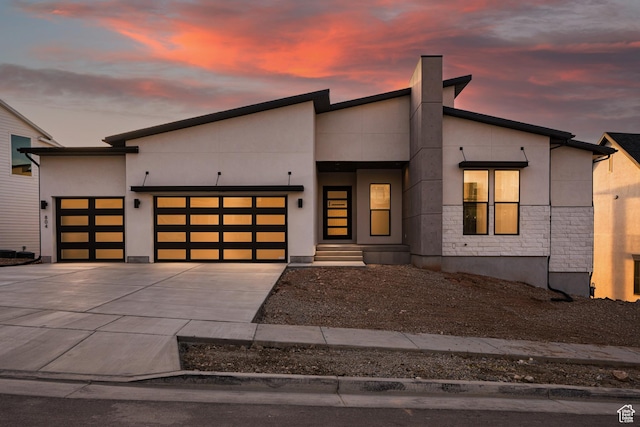contemporary house with driveway, a garage, and stucco siding