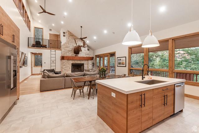 3009 E Black Forest Rd, Sundance, UT 84604 - kitchen with sink, ceiling fan, appliances with stainless steel finishes, a center island with sink, and a stone fireplace