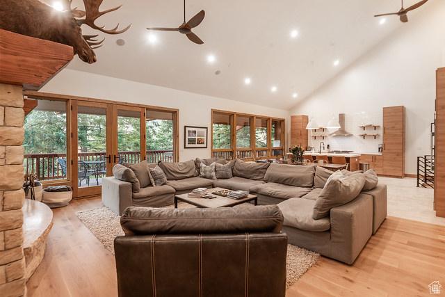 living room with ceiling fan, light wood-type flooring, high vaulted ceiling, and french doors