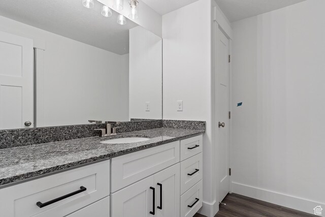 bathroom with vanity, wood finished floors, and baseboards
