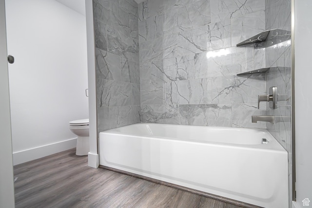 bathroom with baseboards, toilet, wood finished floors, and bathtub / shower combination