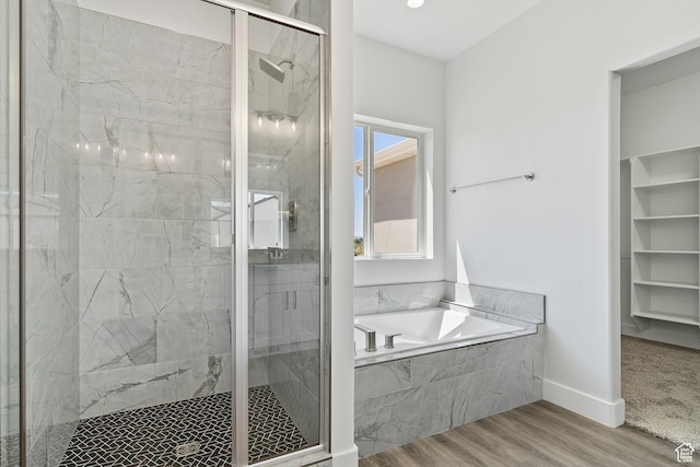 bathroom with a marble finish shower, baseboards, a garden tub, and wood finished floors