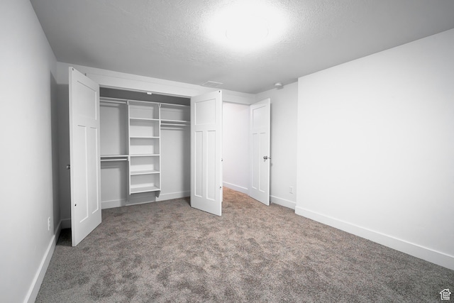 unfurnished bedroom with a closet, a textured ceiling, baseboards, and carpet