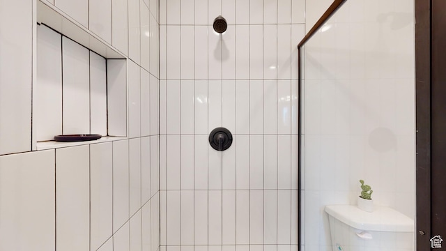 bathroom featuring a tile shower and toilet