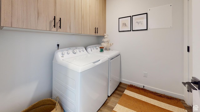 laundry room with light hardwood / wood-style floors, cabinets, and washing machine and dryer