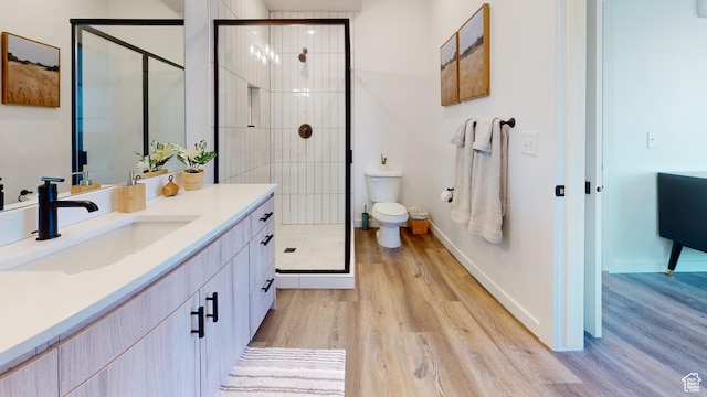 bathroom featuring a shower with door, vanity, wood-type flooring, and toilet
