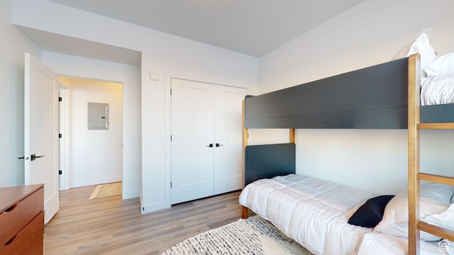 bedroom with electric panel, a closet, and light wood-type flooring