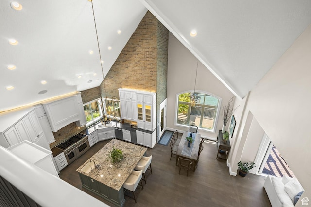 14234 S Canyon Vine Cv E, Draper, UT 84020 - living room featuring high vaulted ceiling, dark wood-type flooring, brick wall, and a notable chandelier