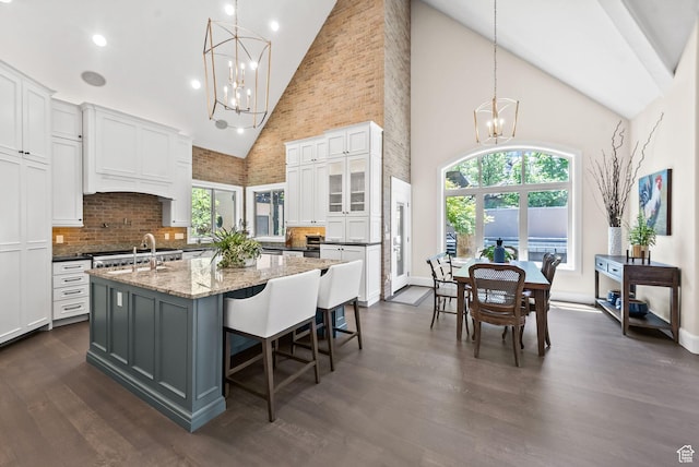 14234 S Canyon Vine Cv E, Draper, UT 84020 - kitchen with a kitchen island with sink, high vaulted ceiling, white cabinets, tasteful backsplash, and decorative light fixtures