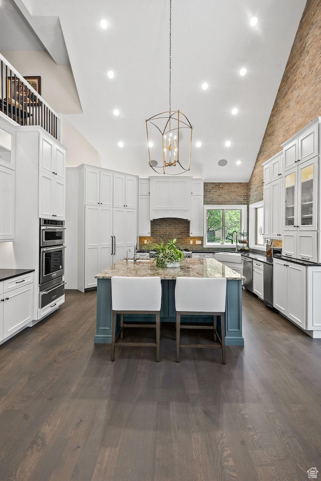 14234 S Canyon Vine Cv E, Draper, UT 84020 - kitchen featuring light stone counters, pendant lighting, high vaulted ceiling, and an island with sink