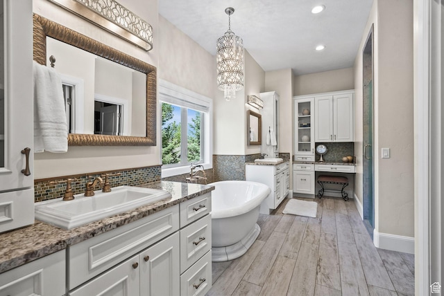 14234 S Canyon Vine Cv E, Draper, UT 84020 - bathroom with backsplash, vanity, a bath, hardwood / wood-style flooring, and an inviting chandelier