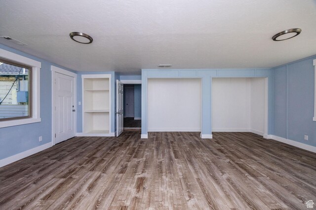 1090 S 2400 W, Lewiston, UT 84320 - unfurnished living room featuring a textured ceiling, visible vents, baseboards, built in shelves, and wood finished floors