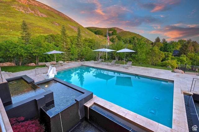 1559 E Tomahawk Dr N, Salt Lake City, UT 84103 - pool at dusk with a mountain view, a patio, and a hot tub