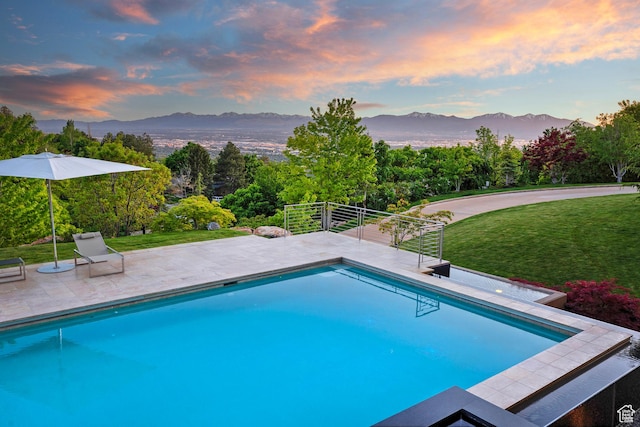 1559 E Tomahawk Dr N, Salt Lake City, UT 84103 - pool at dusk featuring a patio area, a lawn, and a mountain view