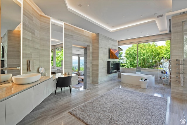 1559 E Tomahawk Dr N, Salt Lake City, UT 84103 - bathroom featuring a tray ceiling, tile walls, a fireplace, vanity, and a bathtub