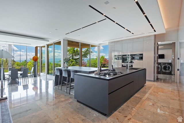 1559 E Tomahawk Dr N, Salt Lake City, UT 84103 - kitchen with appliances with stainless steel finishes, washer and clothes dryer, floor to ceiling windows, sink, and a large island with sink