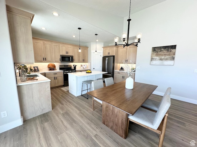 634 E Otto Ln, Grantsville, UT 84029 - kitchen featuring stainless steel gas stove, light brown cabinets, backsplash, a kitchen island, and freestanding refrigerator