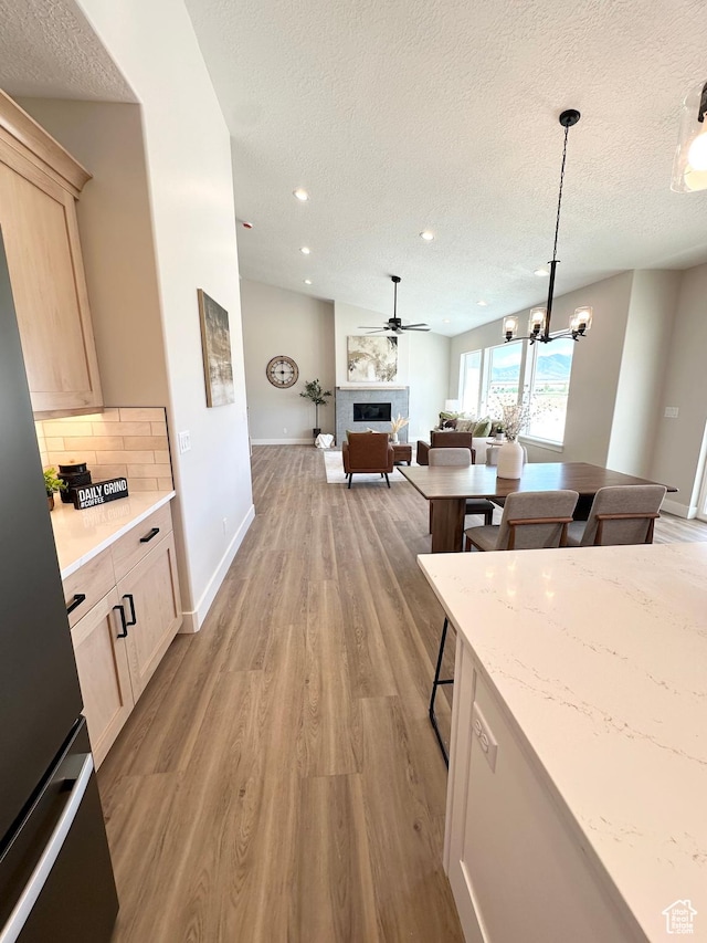 634 E Otto Ln, Grantsville, UT 84029 - kitchen featuring backsplash, light brown cabinetry, open floor plan, light wood-style flooring, and a fireplace