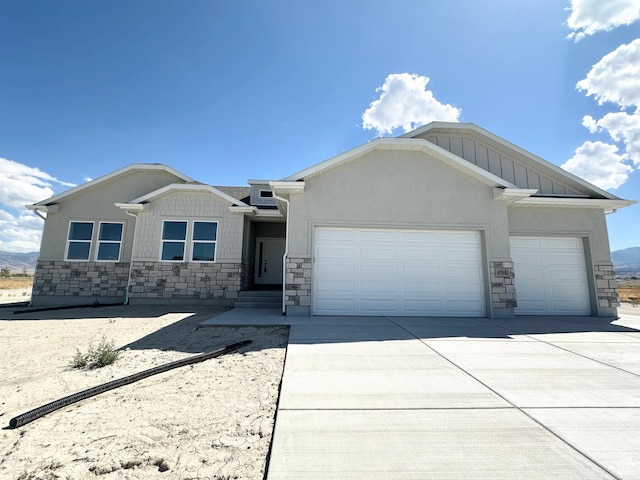 view of front of property with driveway, stucco siding, stone siding, a garage, and board and batten siding