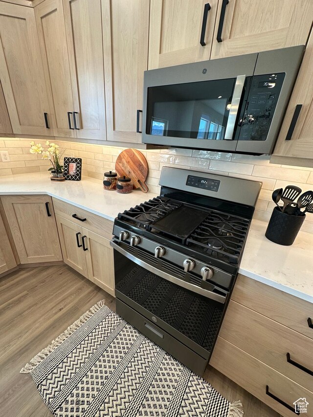 634 E Otto Ln, Grantsville, UT 84029 - kitchen featuring light brown cabinets, light stone counters, decorative backsplash, wood finished floors, and stainless steel appliances