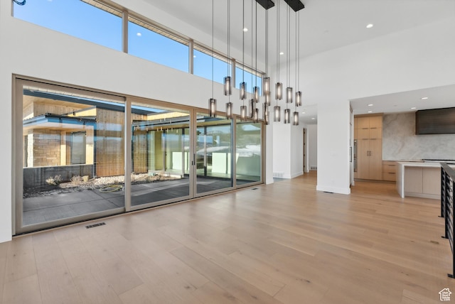 7702 N Fire Ring Glade, Park City, UT 84098 - unfurnished living room featuring a towering ceiling and light hardwood / wood-style flooring