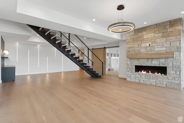 7702 N Fire Ring Glade, Park City, UT 84098 - unfurnished living room featuring wood-type flooring, a barn door, and a stone fireplace
