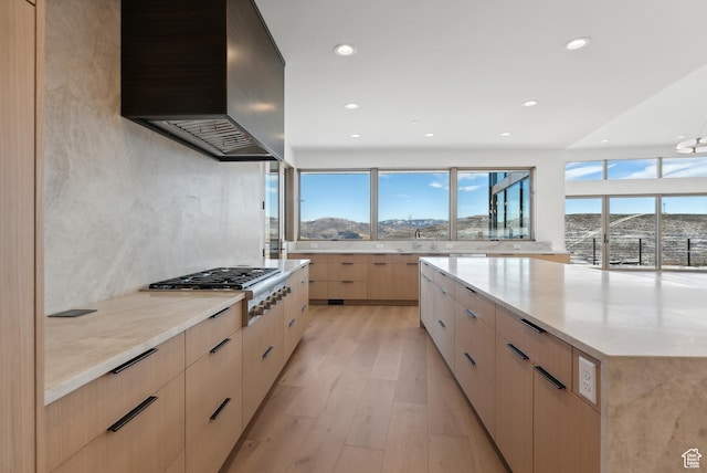 7702 N Fire Ring Glade, Park City, UT 84098 - kitchen featuring light brown cabinetry, light wood-type flooring, wall chimney exhaust hood, stainless steel gas cooktop, and a mountain view