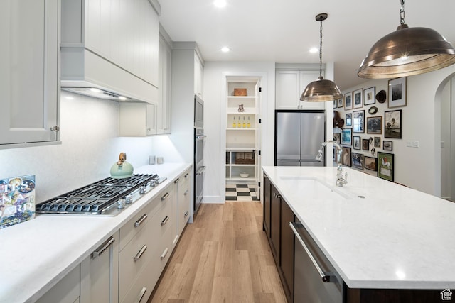 2984 N 1080 W, Lehi, UT 84043 - kitchen with light wood finished floors, a kitchen island with sink, stainless steel appliances, arched walkways, and a sink