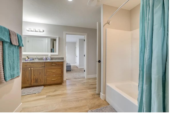 full bathroom with baseboards, shower / bath combo with shower curtain, wood finished floors, and vanity