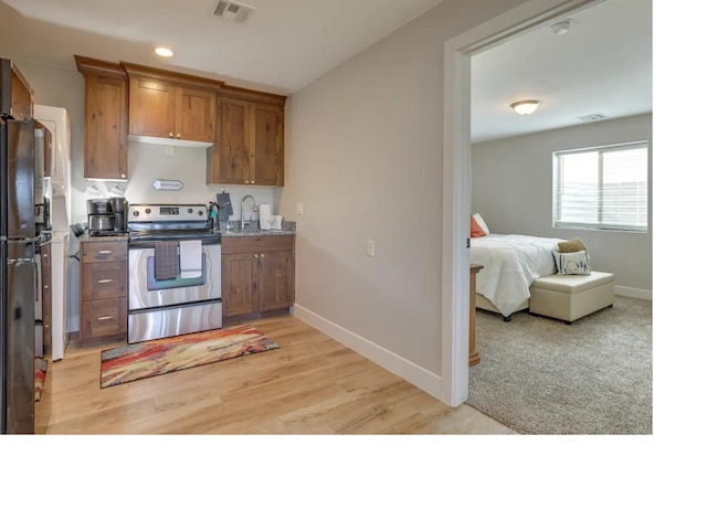 kitchen with a sink, visible vents, baseboards, brown cabinets, and stainless steel range with electric stovetop