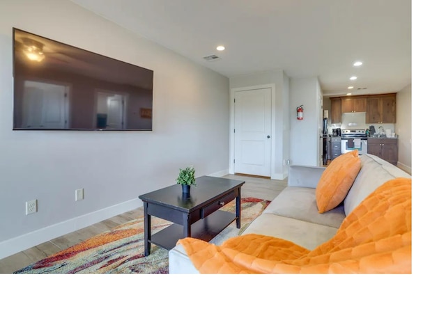 living room featuring light wood finished floors, visible vents, baseboards, and recessed lighting