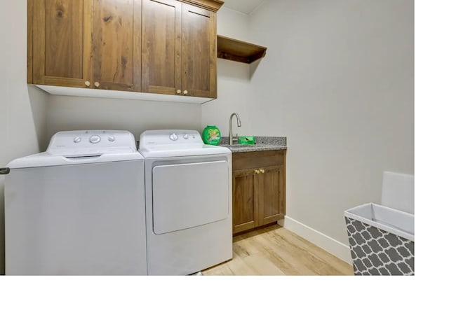 laundry room with cabinet space, light wood finished floors, baseboards, washer and clothes dryer, and a sink
