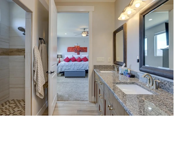 full bathroom featuring double vanity, tiled shower, a sink, and connected bathroom