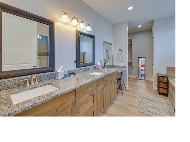 full bathroom featuring double vanity, wood finished floors, a sink, and recessed lighting