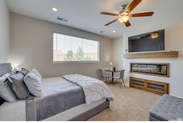 carpeted bedroom featuring recessed lighting, visible vents, baseboards, and a glass covered fireplace