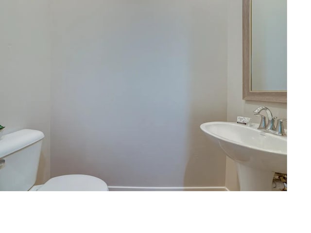 bathroom featuring toilet, baseboards, and a sink
